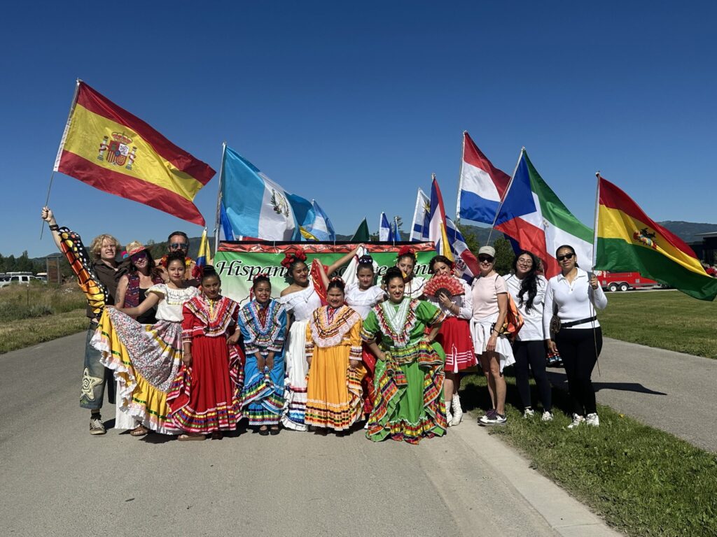 Colorful photo of Hispanic community members wearing traditional dress and holding flags of Hispanic nations.